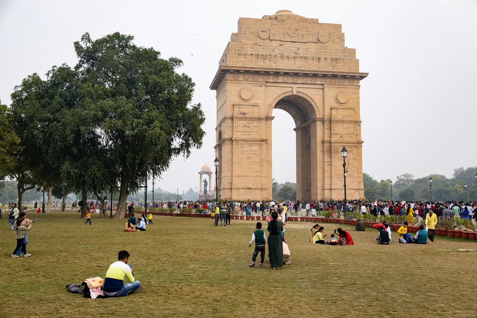 India Gate in New Delhi, with families and visitors relaxing on the lawns in front of it